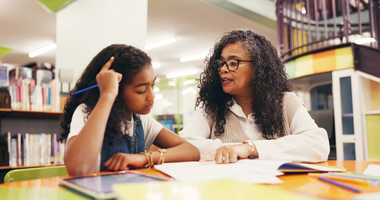 A homeschool student working one-on-one with a tutor at a table with books and learning materials, illustrating tutoring support for homeschool education in Florida.